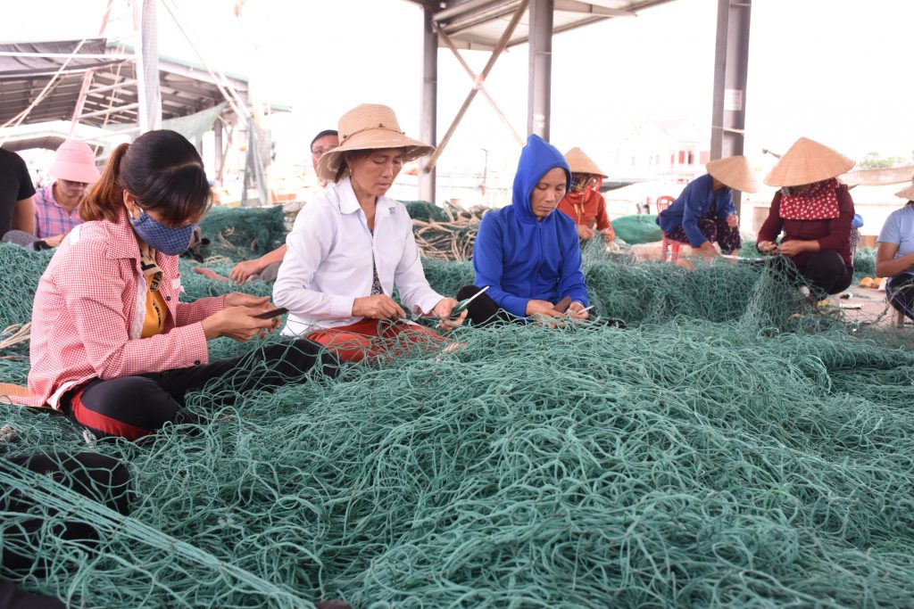 Ngư dân đang vá lại lưới để chuẩn bị cho chuyến ra khơi dài ngày.